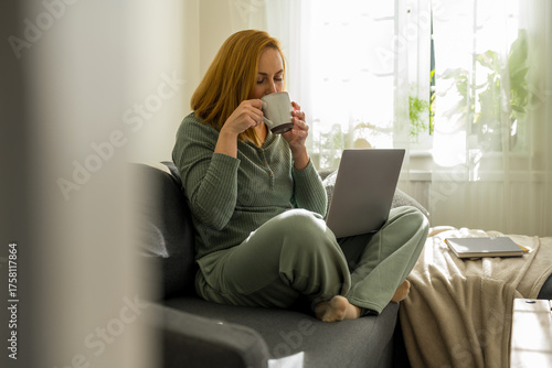woman enjoying her coffee, while working at laptop from home