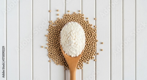 Soy flour and soybeans on a wooden spoon and white surface.