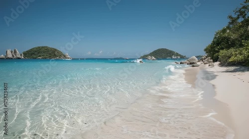 A pristine white sandy beach with crystal-clear turquoise waters and island views