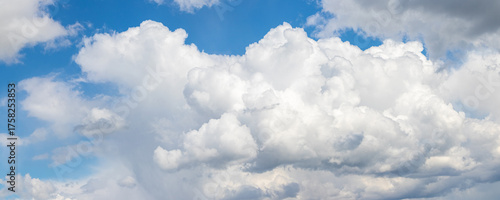 Panoramic view of blue sky with large fluffy cumulonimbus clouds piling up on the horizon line on a sunny day, dramatic sky landscape