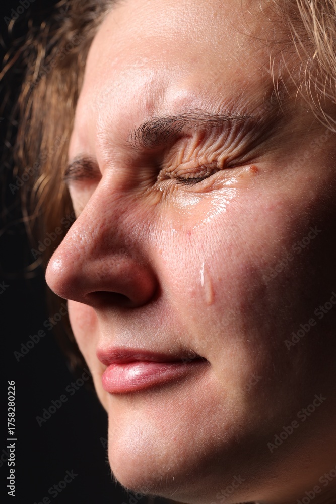 Obraz premium Sad woman crying on black background, closeup