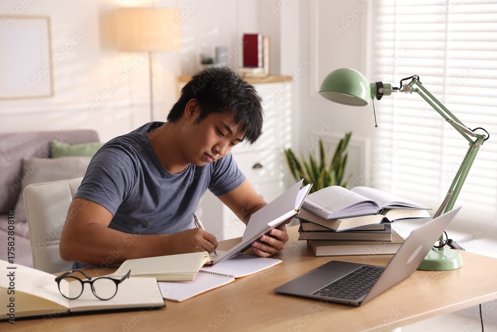 Obraz premium Student with laptop and books preparing for exam at table indoors