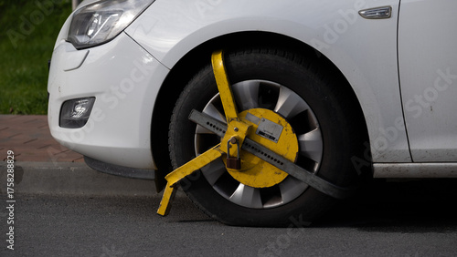 Car wheel locked with yellow clamp on street, Krakow, Poland, October 2025