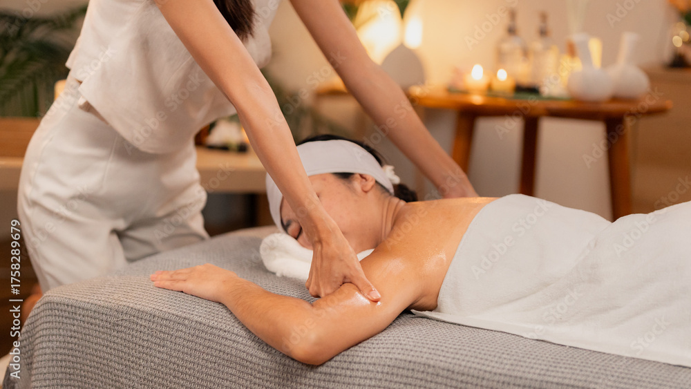 Fototapeta premium Asian Woman Enjoying Relaxing Spa Arm Shoulder Massage Professional Therapist Providing Soothing Treatment Wellness Center Tranquil Environment Body Care