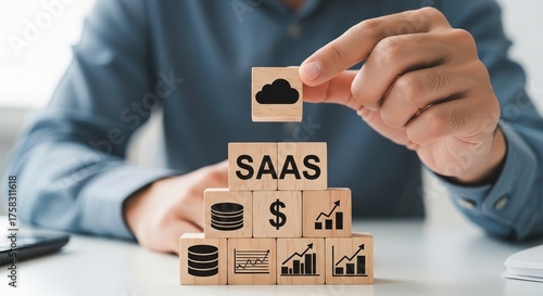 Saas business models, A person is arranging wooden blocks with business icons, the concept of SaaS and financial metrics.