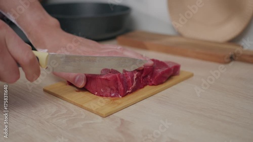 Freshly sliced red meat displayed on a wooden cutting board in a bright kitchen setting, ready for cooking and meal preparation