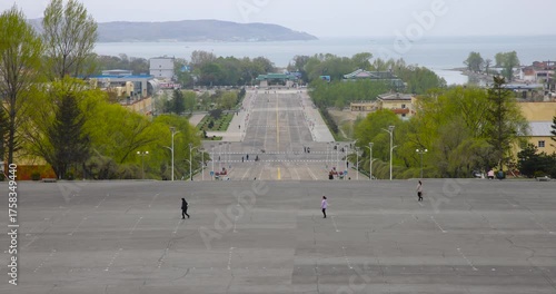 May 8, 2025 - Rason, North Korea - A street in a North Korean border town. Cars and people are moving along a deserted street.