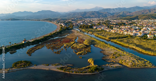 Panoramic aerial drone footage of the stunning Calis Beach and Duck Island wetlands in Fethiye, Turkey. This cinematic sunset view showcases the town, sea, and mountains in the background.