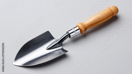 A shiny, stainless steel garden trowel with a wooden handle, designed for digging and planting in soil.