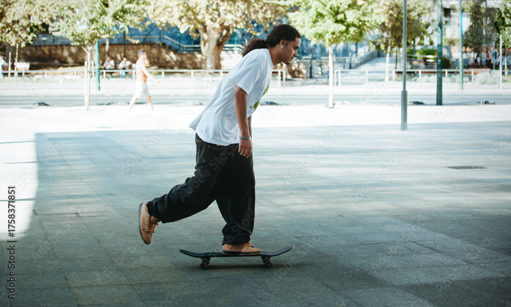 Fototapeta premium Young skater cruising through the city on a sunny afternoon
