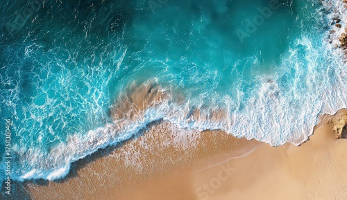 Aerial View of Turquoise Ocean Waves Crashing on Sandy Beach with Golden Sunlight Reflecting