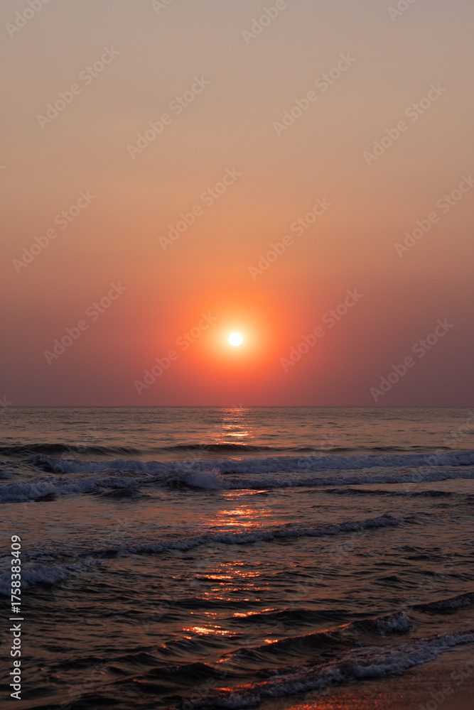 Fototapeta premium A tranquil sunset over the sea, painting the horizon with warm orange and pink colors