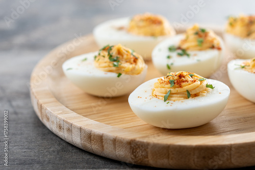 Homemade hard Boiled Deviled Eggs garnished with herbs on wooden table
