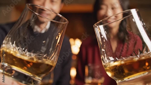 People Clinking Whiskey Glasses at Cozy Gathering in Warm Lighting