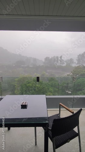 Black table and chairs on the balcony in the rain