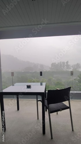 Black table and chairs on the balcony in the rain