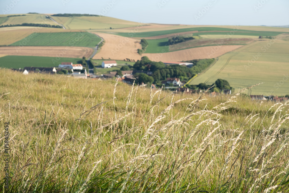 Fototapeta premium Cap Blanc-Nez, Escalles, Pas-de-Calais, Hauts-de-France, France, July 29th, 2025, Experience a breathtaking view of the lush, rolling hills and a quaint village beautifully set under clear blue skies