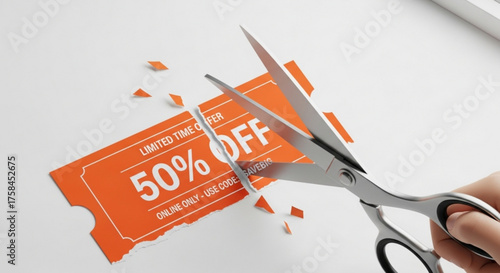 Closeup of hand cutting a 50 off discount coupon with scissors, limited time offer, online only, use code savebig