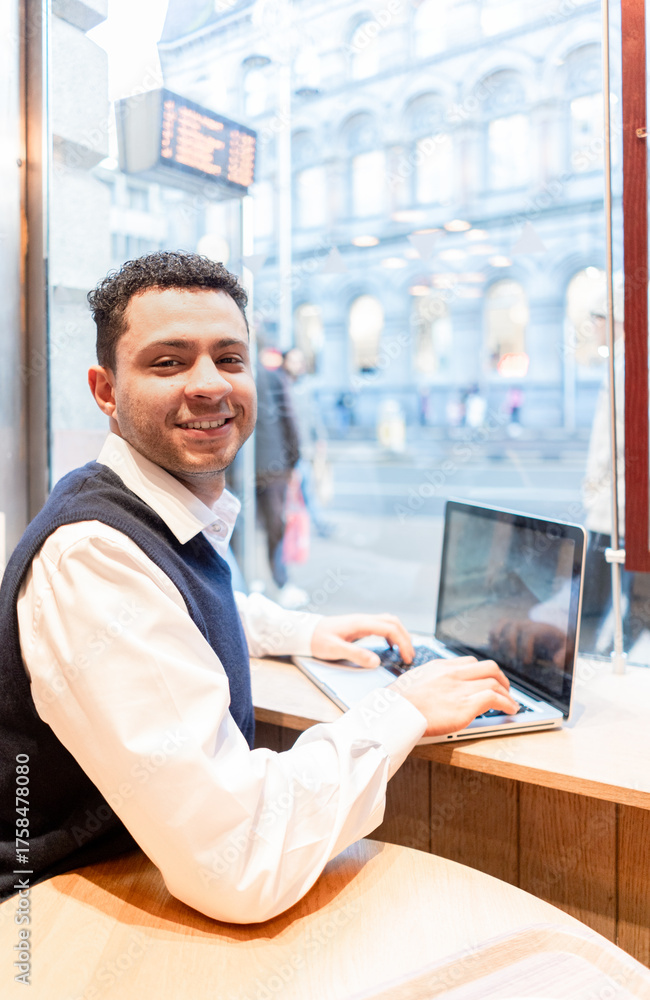 Fototapeta premium A young elegant executive of mixed ethnicity smiles at the camera, holding a laptop in historic Dublin.