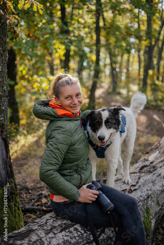 Photographer and hiker woman enjoying walking her dog off-leash in an autumn forest. 