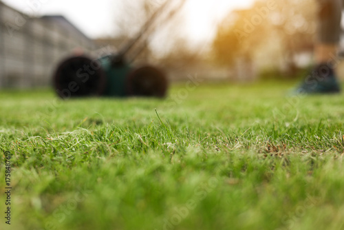 Gardening work tools. Green electric aerator scarifier for soil cultivation and compaction on bright lush green lawn grass. Professional lawn care service. Grass maintenance. Place for text.