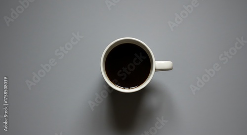 Overhead view of a white ceramic mug filled with dark liquid on gray surface