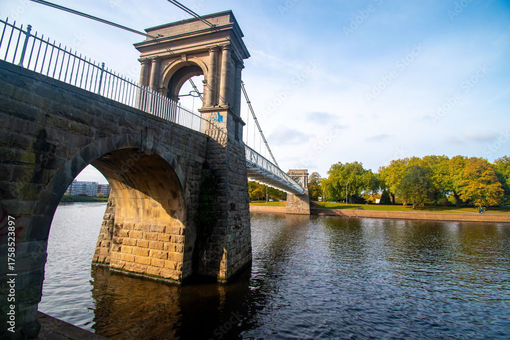 Obraz premium A view of Wilford Suspension bridge over the river Trent in Nottingham from the Victoria Embankment.