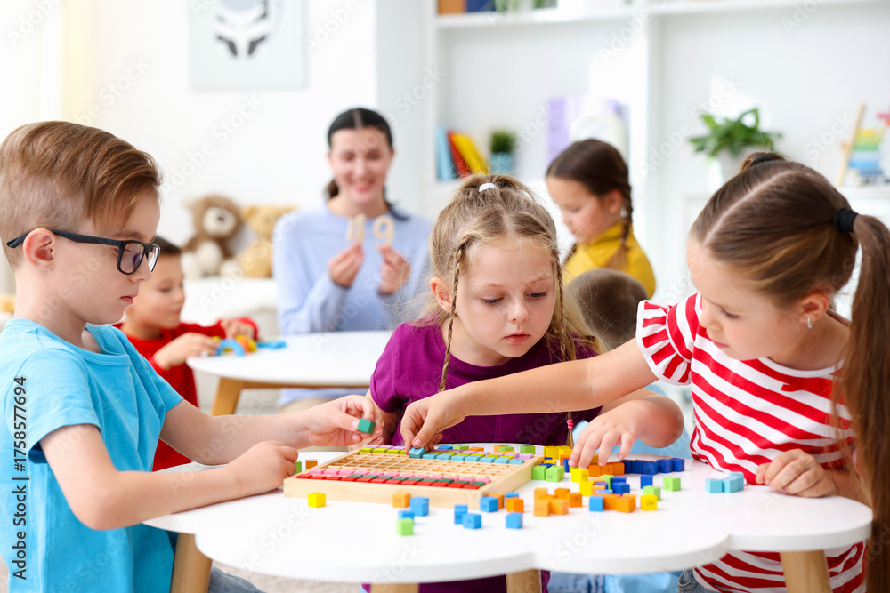 Naklejka premium Cute children and teacher at white tables during lesson in elementary school