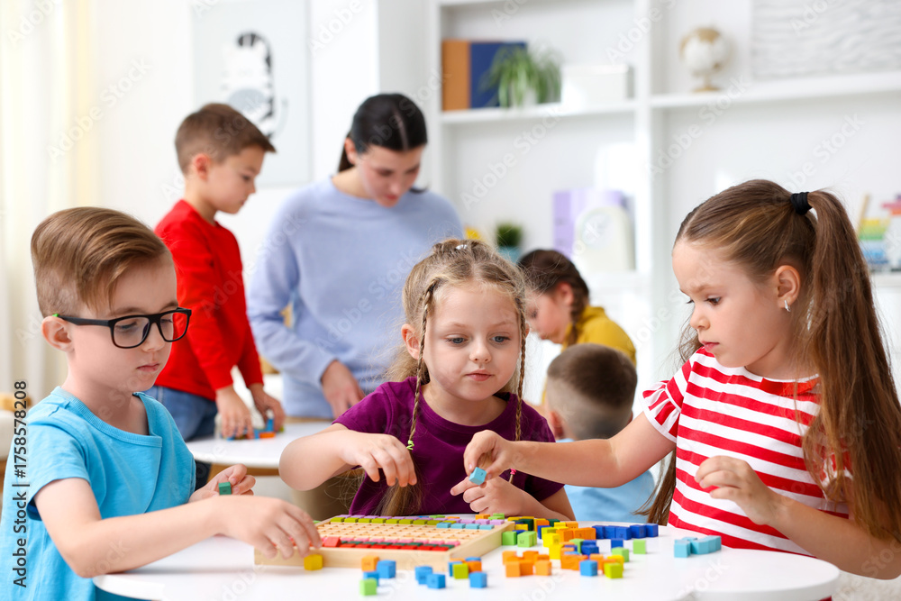 Fototapeta premium Cute children and teacher at white tables during lesson in elementary school