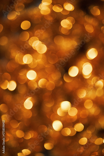 Golden bokeh lights creating festive abstract background with warm glowing circles evoking Christmas holiday atmosphere suitable for seasonal designs and celebratory visuals