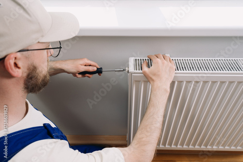 Canvastavla Man performs maintenance on home heating radiator for optimal warmth during wint