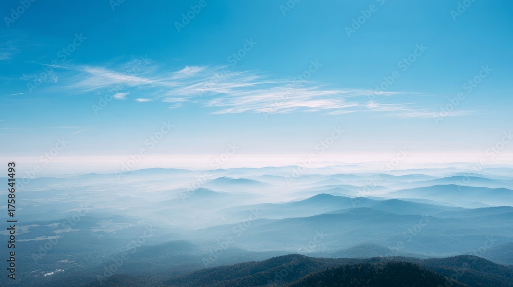 Fototapeta premium Expansive view of majestic mountain peaks and serene blue sky with delicate clouds.
