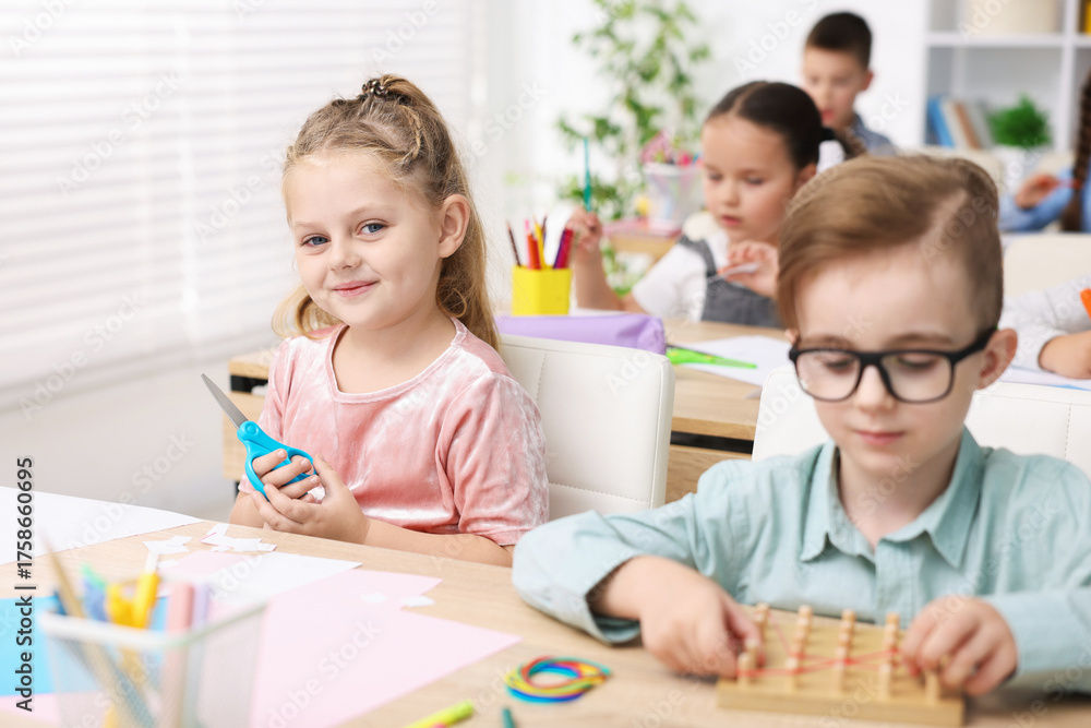 Fototapeta premium Cute children at wooden desks during lesson in elementary school