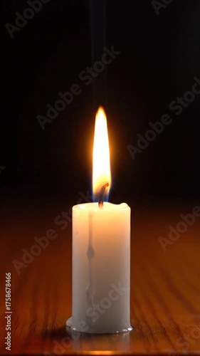 Burning candle on wooden surface with black background overhead shot