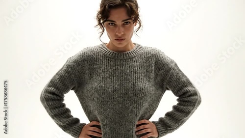 Woman with hands on hips looking at the camera with a serious expression.