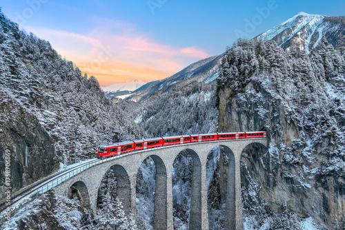 Fototapeta Naklejka Na Ścianę i Meble -  Aerial view of Train passing through famous mountain in Filisur, Switzerland. Landwasser Viaduct world heritage with train express in Swiss Alps snow winter scenery.