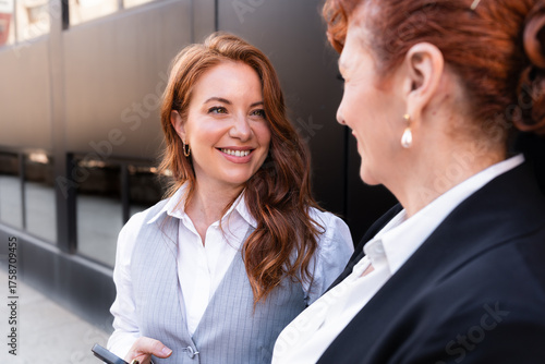 Smiling adult daughter talking to mother businesswoman outside office