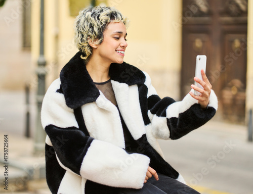 Young woman taking selfie with smartphone in city