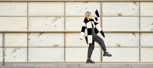 Young woman confidently walking wearing stylish checkerboard coat