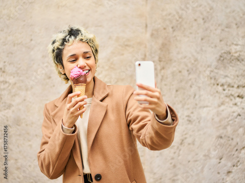 Woman enjoying ice cream and taking selfie outdoors