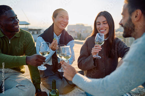 Tableau sur toile Four diverse friends raising wine glasses, celebrating and socializing together