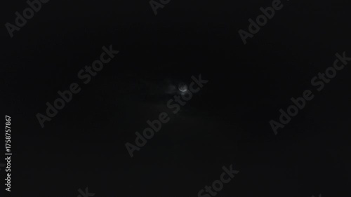 A time lapse shot of the dark monsoon or rain clouds passing in front of the moon in the night