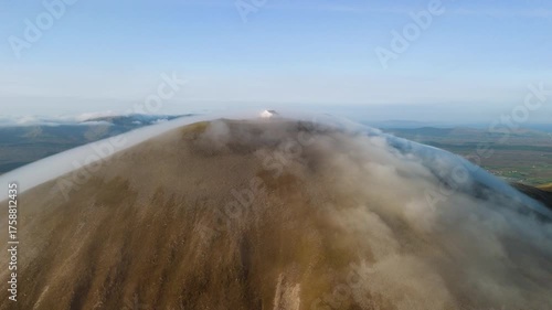 Amazing 4K aerial video of flying above and around Most Famous mountain in Ireland - Croagh Patrick in windy weather, with moving fog and clouds with breathtaking views around, Westport, Ireland