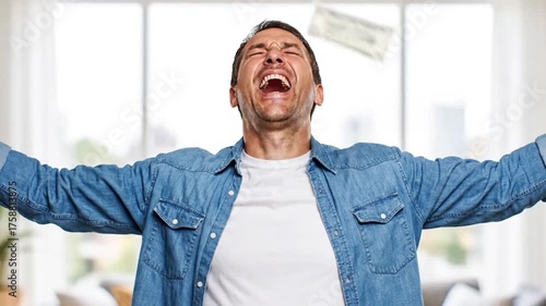 An ecstatic and overjoyed man in a denim shirt celebrates a financial windfall, shouting with pure joy and arms outstretched as money rains down. A concept of success, winning the lottery.