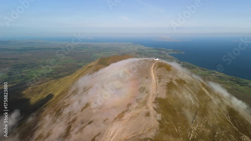 Amazing 4K aerial video of flying above and around Most Famous mountain in Ireland - Croagh Patrick in windy weather, with moving fog and clouds with breathtaking views around, Westport, Ireland