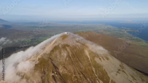 Amazing 4K aerial video of flying above and around Most Famous mountain in Ireland - Croagh Patrick in windy weather, with moving fog and clouds with breathtaking views around, Westport, Ireland