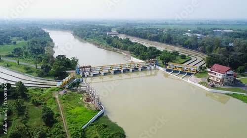 Aerial drone shot of the Rentang Dam/Weir in Majalengka, Indonesia. It shows the structure, including the sluice gates, water channels, and surrounding green areas.