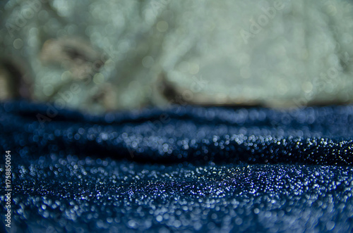 A bright holiday template. Background for congratulations. Gold and black shiny fabric. A screen saver with a Bokeh. A cold shade.