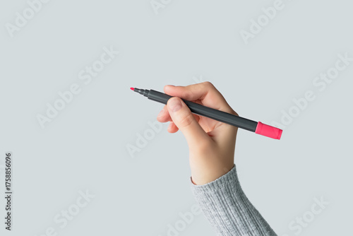 Hand holding a red marker pen ready to write isolated on gray background