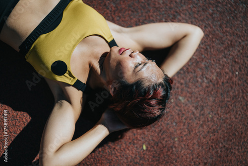 Photos Fitness enthusiast recovering after exercise on a track, relaxation and perseverance depicted